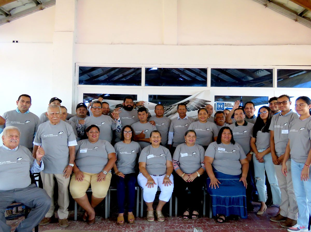 A group of lined-up people in matching gray shirts pose for the camera.