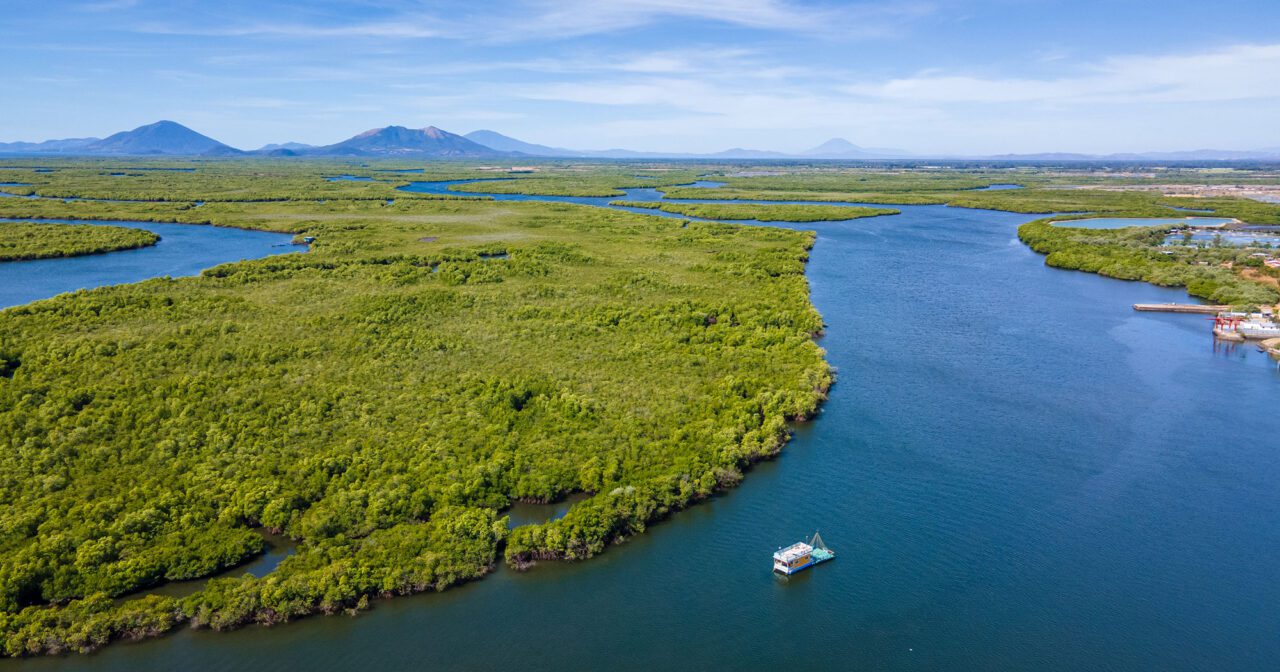 Beautiful vsta of a blue-water bay with green islands of land and mountains in the distance.