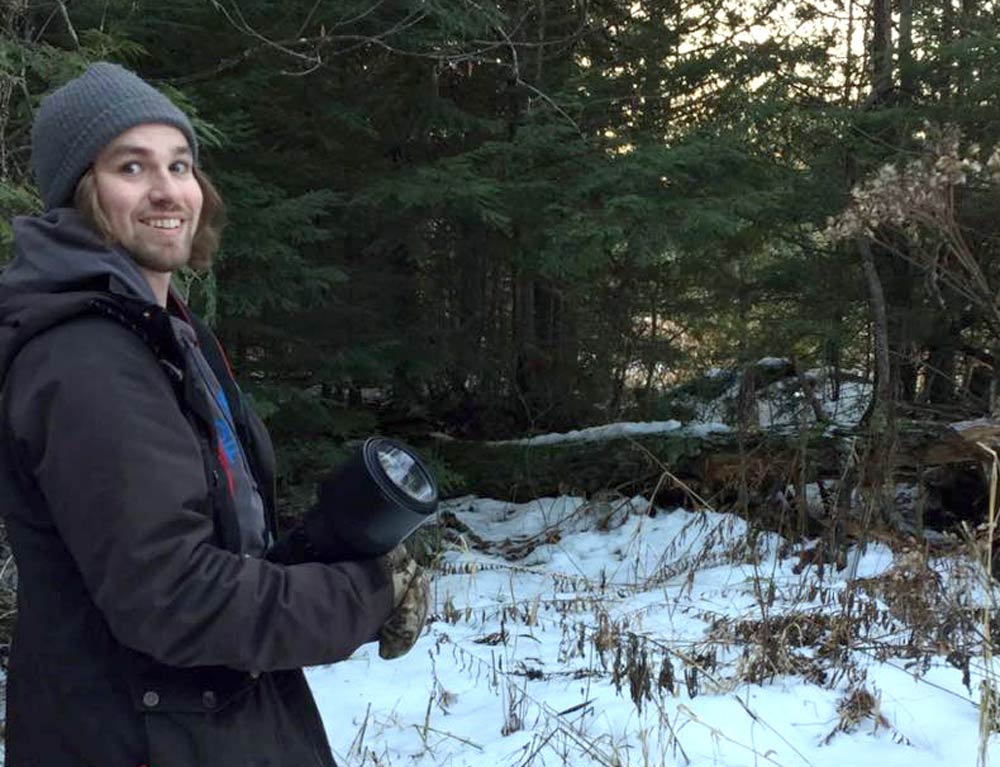 a person holding a camera stands in a snowy forest